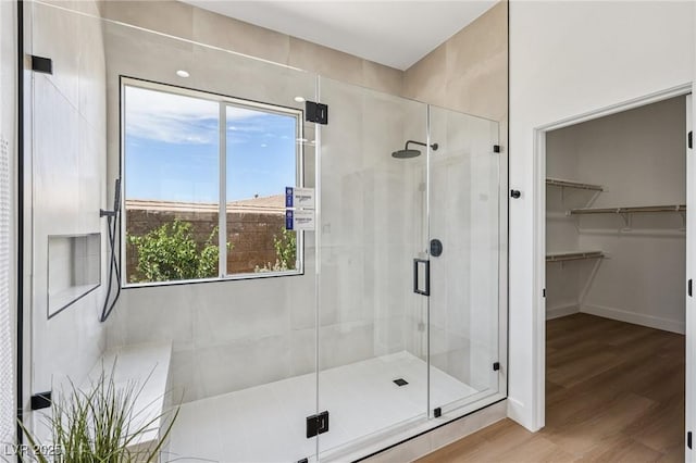 2297 Aria Dr, Henderson, NV 89052 - bathroom featuring healthy amount of natural light, a shower stall, wood finished floors, and a walk in closet