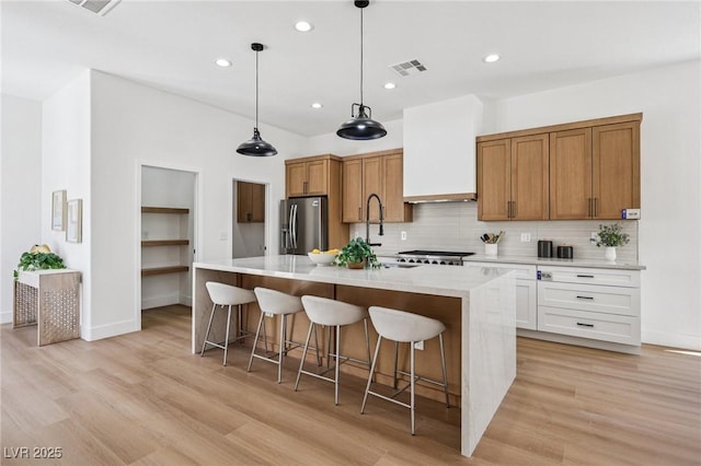 2297 Aria Dr, Henderson, NV 89052 - kitchen with stainless steel fridge with ice dispenser, backsplash, light wood finished floors, a breakfast bar area, and recessed lighting