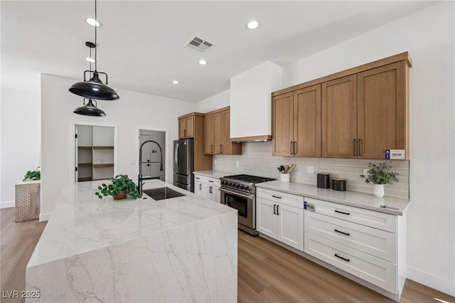 2297 Aria Dr, Henderson, NV 89052 - kitchen with appliances with stainless steel finishes, tasteful backsplash, light wood finished floors, light stone counters, and pendant lighting
