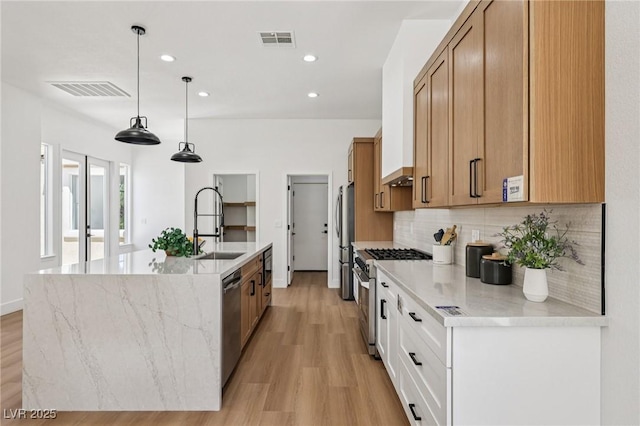 2297 Aria Dr, Henderson, NV 89052 - kitchen with appliances with stainless steel finishes, tasteful backsplash, an island with sink, light wood-style floors, and recessed lighting