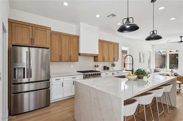 2297 Aria Dr, Henderson, NV 89052 - kitchen featuring appliances with stainless steel finishes, light wood-style floors, an island with sink, light stone counters, and recessed lighting