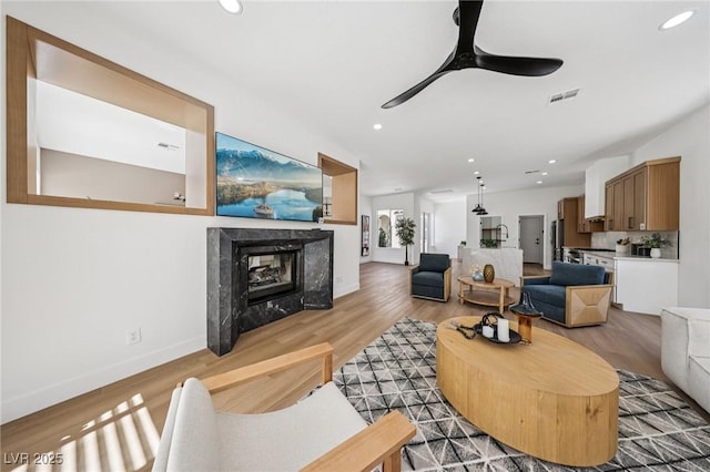 2297 Aria Dr, Henderson, NV 89052 - living area with light wood finished floors, a ceiling fan, recessed lighting, and a high end fireplace