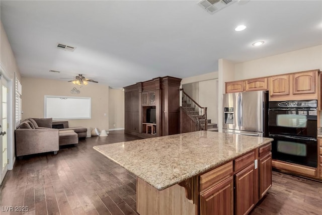 1054 Broomfield Dr, Henderson, NV 89074 - kitchen with stainless steel fridge, light stone counters, ceiling fan, a kitchen island, and dark wood finished floors