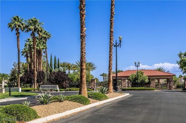 7889 Rancho Mirage Dr, Las Vegas, NV 89113 - view of asphalt road with a gate, a gated entry, street lighting, and curbs