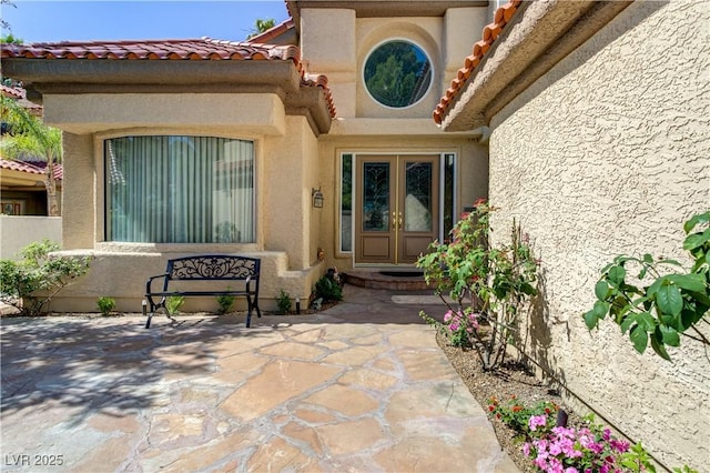7889 Rancho Mirage Dr, Las Vegas, NV 89113 - view of exterior entry with french doors, stucco siding, a tiled roof, and a patio area
