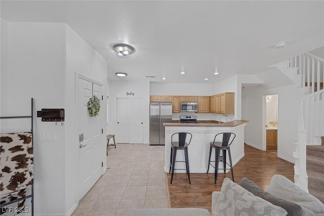 8639 Horizon Wind Ave Unit 102, Las Vegas, NV 89178 - kitchen featuring stainless steel appliances, a peninsula, a breakfast bar area, and light tile patterned floors