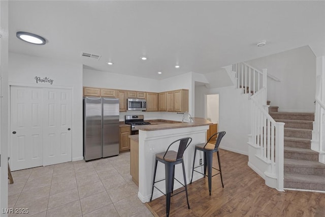 8639 Horizon Wind Ave Unit 102, Las Vegas, NV 89178 - kitchen with stainless steel appliances, a kitchen breakfast bar, recessed lighting, a peninsula, and light brown cabinetry