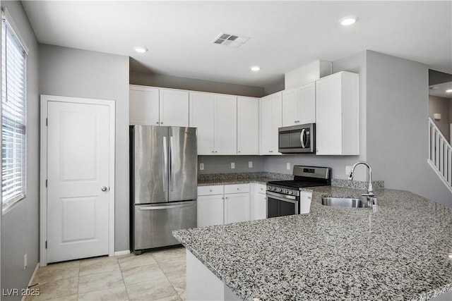7990 Formitch Ct, Las Vegas, NV 89166 - kitchen with stainless steel appliances, a peninsula, light stone countertops, white cabinets, and recessed lighting