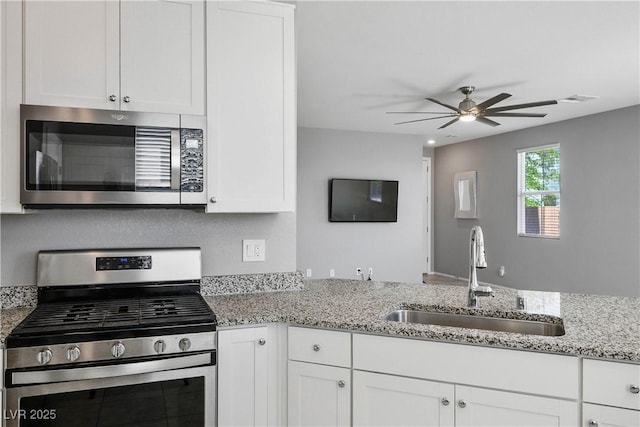 7990 Formitch Ct, Las Vegas, NV 89166 - kitchen with stainless steel appliances, ceiling fan, white cabinetry, and light stone counters