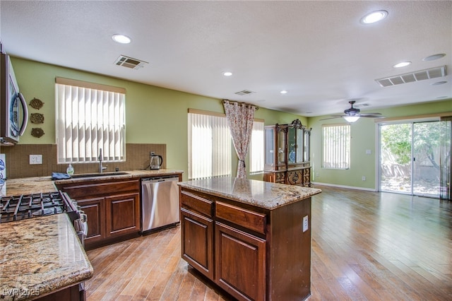 9022 Sosa Creek Ave, Las Vegas, NV 89149 - kitchen featuring appliances with stainless steel finishes, light wood-style floors, tasteful backsplash, light stone counters, and recessed lighting
