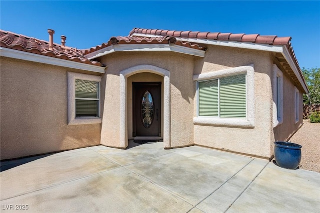 6740 Arctic Breeze St, North Las Vegas, NV 89084 - view of exterior entry featuring a patio area, a tiled roof, and stucco siding