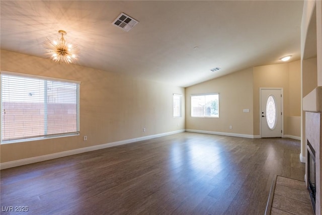 6740 Arctic Breeze St, North Las Vegas, NV 89084 - unfurnished living room with dark wood-type flooring, a chandelier, lofted ceiling, and a tiled fireplace