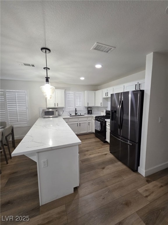 332 Dockside Ct, Las Vegas, NV 89145 - kitchen featuring appliances with stainless steel finishes, a peninsula, white cabinets, decorative light fixtures, and a textured ceiling