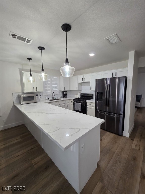 332 Dockside Ct, Las Vegas, NV 89145 - kitchen with appliances with stainless steel finishes, a peninsula, white cabinets, light stone countertops, and dark wood-style flooring