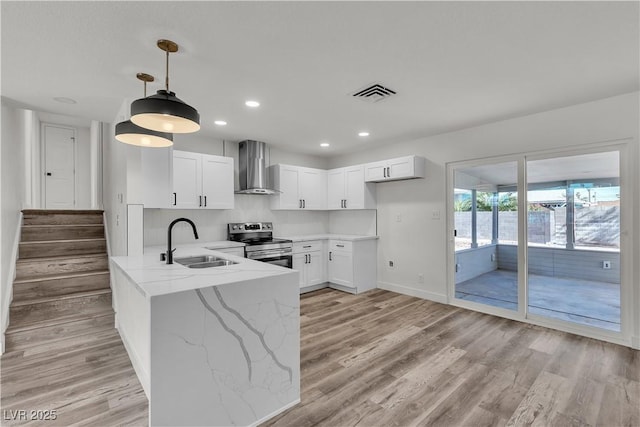 5617 Reiter Ave, Las Vegas, NV 89108 - kitchen with wall chimney exhaust hood, stainless steel range with electric cooktop, a peninsula, light stone countertops, and white cabinets