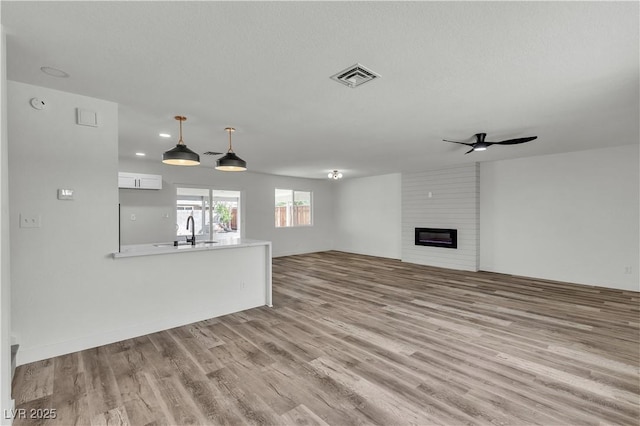 5617 Reiter Ave, Las Vegas, NV 89108 - unfurnished living room with wood finished floors, ceiling fan, and a fireplace