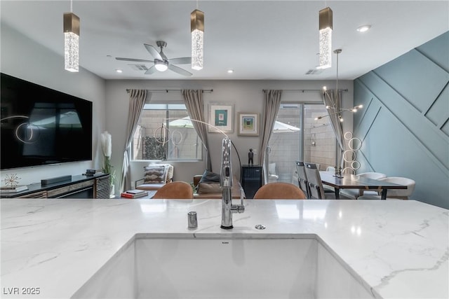 2530 Catallo St, Henderson, NV 89044 - kitchen featuring light stone counters, ceiling fan, healthy amount of natural light, and hanging light fixtures