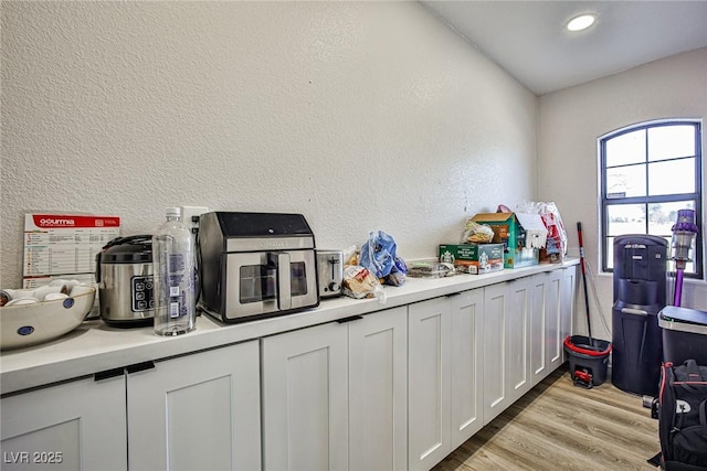 9340 W Washburn Rd, Las Vegas, NV 89149 - kitchen featuring light countertops, white cabinets, light wood-type flooring, a textured wall, and recessed lighting