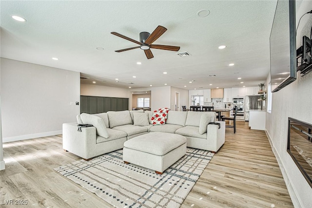 9340 W Washburn Rd, Las Vegas, NV 89149 - living room with ceiling fan, a glass covered fireplace, recessed lighting, and light wood finished floors