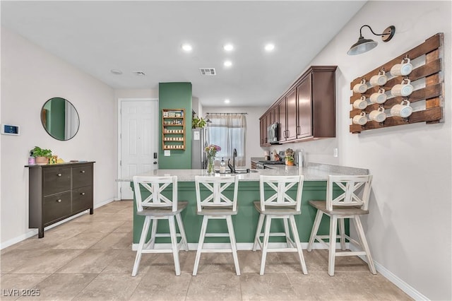 4332 Stardusk Falls Ave, North Las Vegas, NV 89084 - kitchen with dark brown cabinets, light countertops, a peninsula, a breakfast bar, and recessed lighting