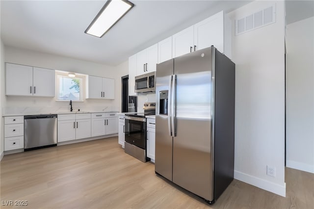 5617 Alfred Dr, Las Vegas, NV 89108 - kitchen with stainless steel appliances, light countertops, light wood-type flooring, and white cabinets