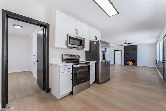 5617 Alfred Dr, Las Vegas, NV 89108 - kitchen with stainless steel appliances, light wood-type flooring, light countertops, open floor plan, and white cabinetry