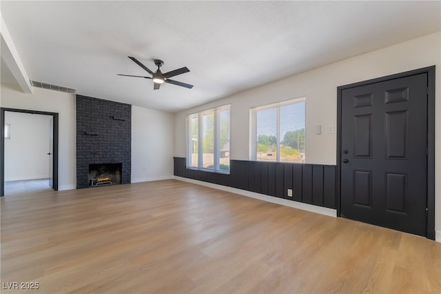 5617 Alfred Dr, Las Vegas, NV 89108 - unfurnished living room featuring ceiling fan, light wood finished floors, a brick fireplace, and a wainscoted wall
