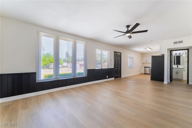 5617 Alfred Dr, Las Vegas, NV 89108 - unfurnished living room with light wood-style flooring, ceiling fan, and a wainscoted wall