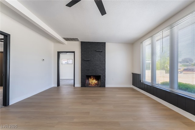 5617 Alfred Dr, Las Vegas, NV 89108 - unfurnished living room featuring a ceiling fan, light wood-style floors, a brick fireplace, and beamed ceiling