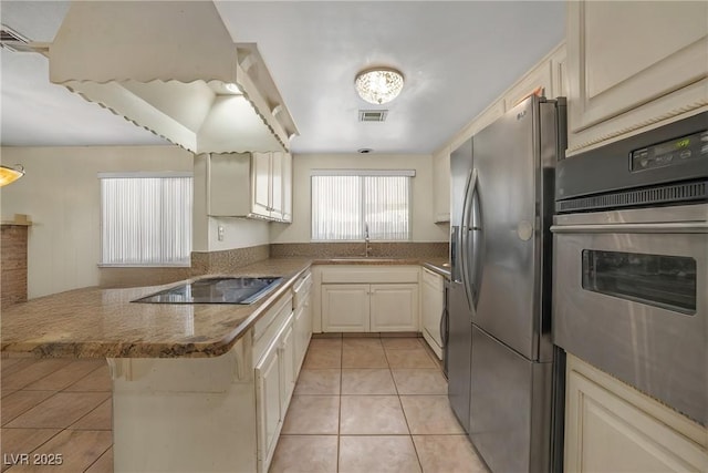 2009 E Oakey Blvd, Las Vegas, NV 89104 - kitchen featuring appliances with stainless steel finishes, a peninsula, light tile patterned floors, and stone counters