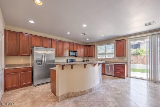 4016 Gaster Ave, North Las Vegas, NV 89081 - kitchen with appliances with stainless steel finishes, a breakfast bar, a kitchen island, brown cabinets, and recessed lighting