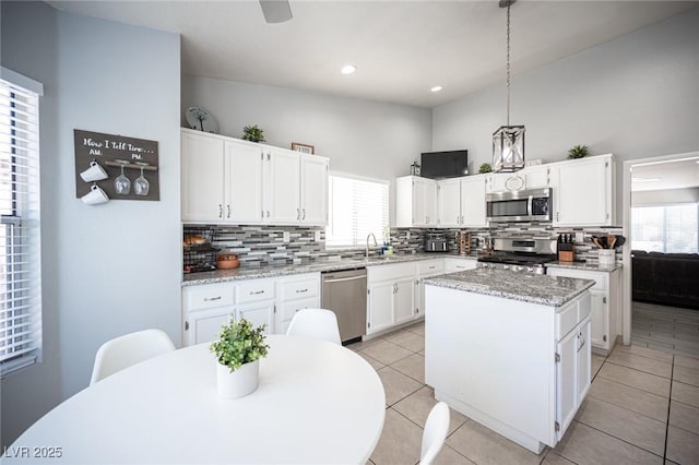 1553 Bright View Dr, Las Vegas, NV 89119 - kitchen featuring appliances with stainless steel finishes, decorative backsplash, a kitchen island, white cabinets, and plenty of natural light