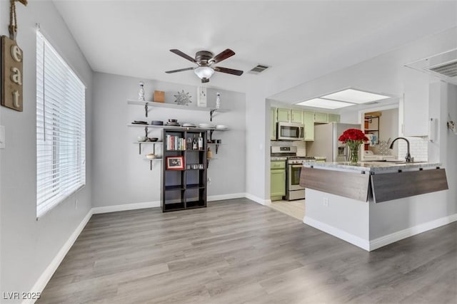 7100 Pirates Cove Rd Unit 2076, Las Vegas, NV 89145 - kitchen with stainless steel appliances, a ceiling fan, light wood finished floors, and a peninsula