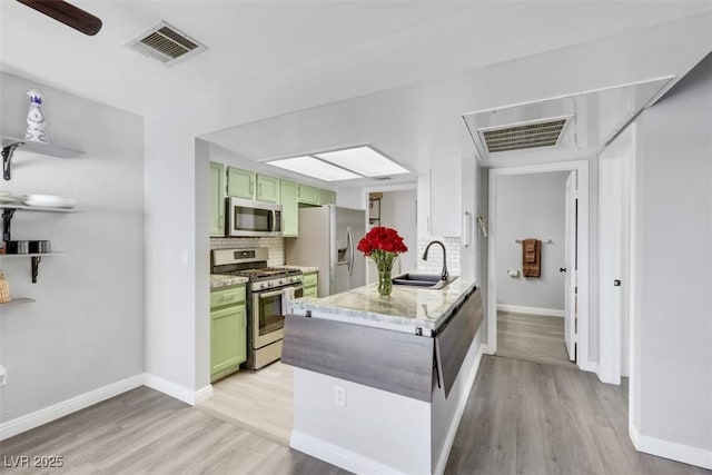 7100 Pirates Cove Rd Unit 2076, Las Vegas, NV 89145 - kitchen featuring green cabinetry, appliances with stainless steel finishes, light wood-type flooring, backsplash, and a peninsula
