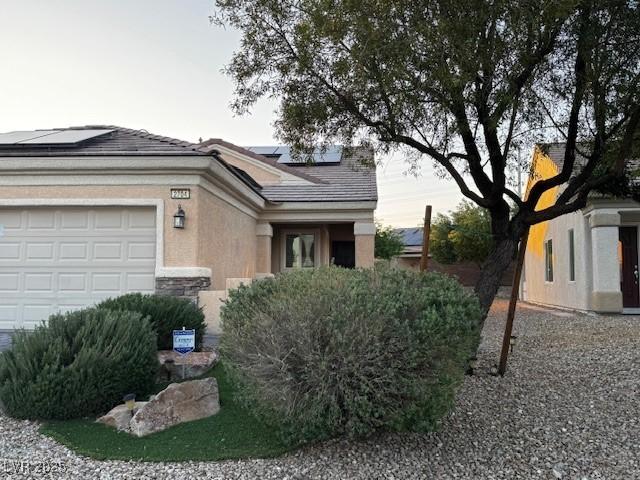 2704 Willow Wren Dr, North Las Vegas, NV 89084 - view of home's exterior with roof mounted solar panels, stucco siding, a garage, and stone siding