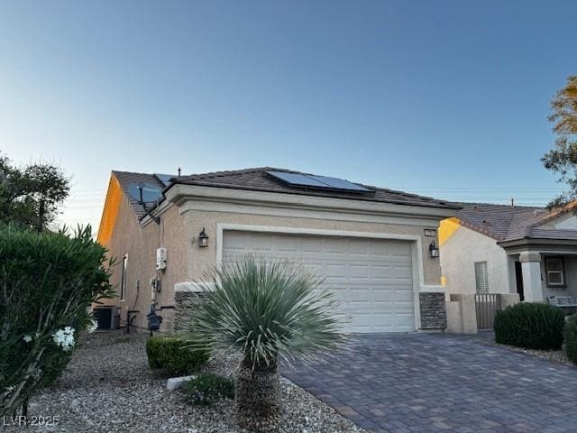 2704 Willow Wren Dr, North Las Vegas, NV 89084 - view of front of home featuring stucco siding, an attached garage, solar panels, and decorative driveway