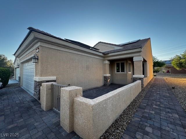 2704 Willow Wren Dr, North Las Vegas, NV 89084 - view of side of home featuring stucco siding, an attached garage, and driveway