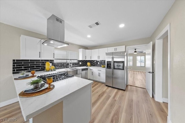 321 Oil Lantern Ln, Las Vegas, NV 89145 - kitchen with stainless steel appliances, island exhaust hood, decorative backsplash, light stone counters, and white cabinets