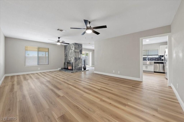 321 Oil Lantern Ln, Las Vegas, NV 89145 - unfurnished living room featuring light wood finished floors, a ceiling fan, and a fireplace