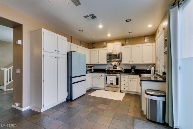 4512 Long Horse Ct, Las Vegas, NV 89147 - kitchen with appliances with stainless steel finishes, dark countertops, white cabinetry, recessed lighting, and dark stone finish flooring