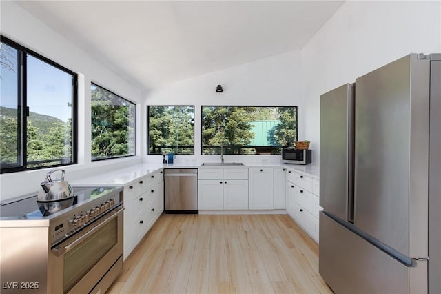 4778 Knotty Pine Way, Las Vegas, NV 89124 - kitchen with stainless steel appliances, white cabinetry, lofted ceiling, plenty of natural light, and light wood-type flooring