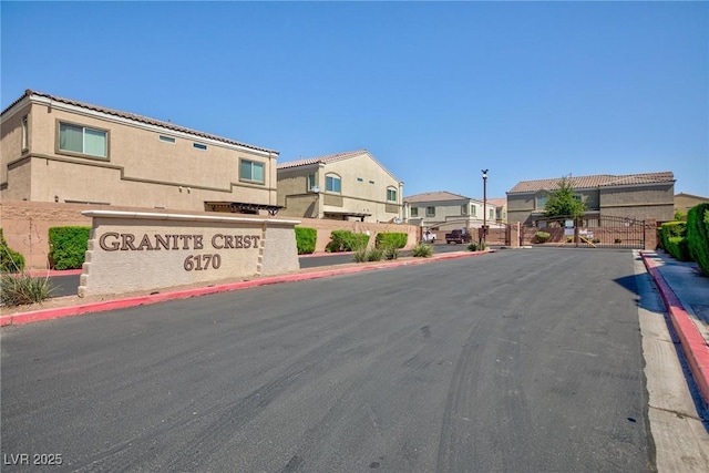 6170 E Sahara Ave Unit 1076, Las Vegas, NV 89142 - view of asphalt street with curbs, a residential view, a gated entry, sidewalks, and street lights
