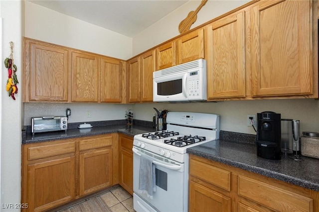 6170 E Sahara Ave Unit 1076, Las Vegas, NV 89142 - kitchen featuring white appliances, light tile patterned flooring, and dark countertops