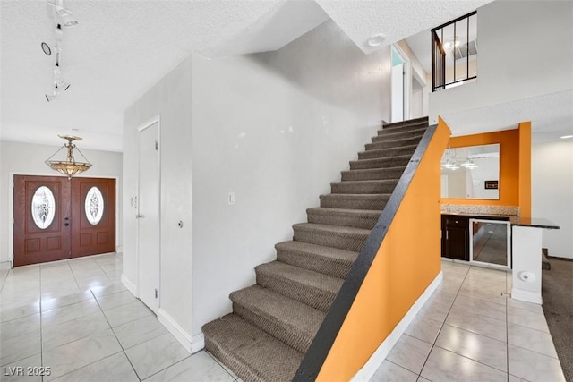 1385 Morning Sun Way, Las Vegas, NV 89110 - stairway featuring a textured ceiling, tile patterned flooring, wine cooler, and track lighting