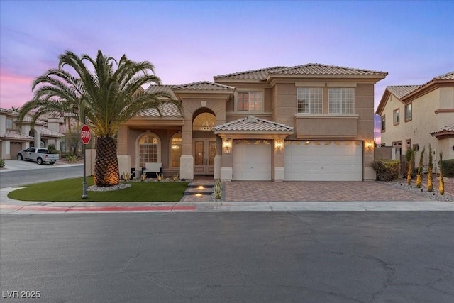 8970 Lansberry Ct, Las Vegas, NV 89147 - mediterranean / spanish house featuring an attached garage, decorative driveway, stucco siding, and a tile roof