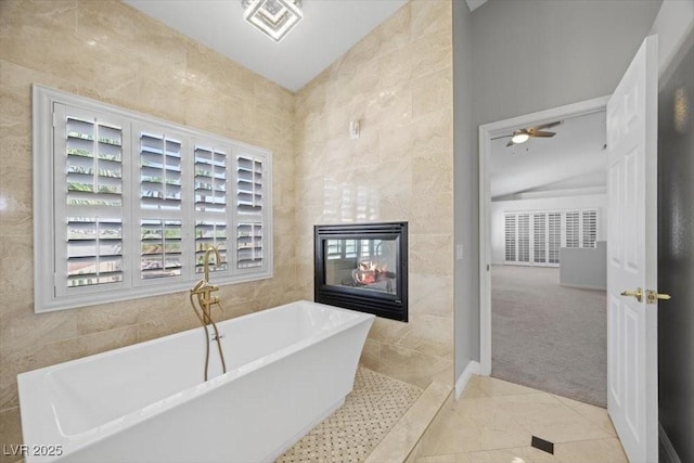 8970 Lansberry Ct, Las Vegas, NV 89147 - full bathroom with tile walls, a soaking tub, a tiled fireplace, tile patterned floors, and a ceiling fan