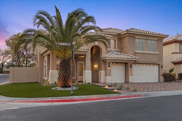 8970 Lansberry Ct, Las Vegas, NV 89147 - mediterranean / spanish-style house featuring a garage, decorative driveway, stucco siding, a tile roof, and a lawn