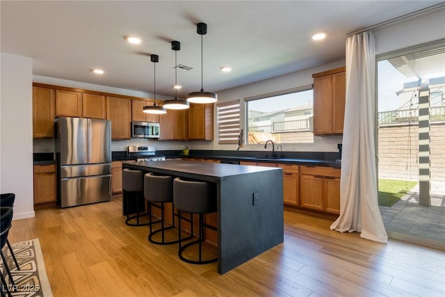 6927 Desert Finch St, North Las Vegas, NV 89084 - kitchen featuring appliances with stainless steel finishes, dark countertops, light wood-type flooring, brown cabinets, and recessed lighting