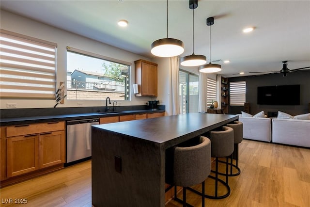 6927 Desert Finch St, North Las Vegas, NV 89084 - kitchen featuring dishwasher, dark countertops, a center island, light wood-type flooring, and a kitchen bar
