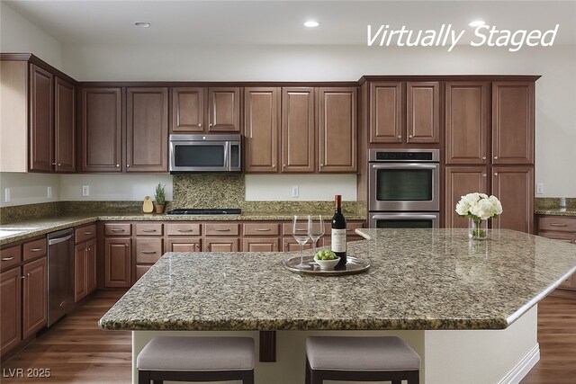 8604 Amber Autumn St, Las Vegas, NV 89131 - kitchen with stainless steel appliances, dark wood-type flooring, a kitchen island, a breakfast bar area, and stone countertops